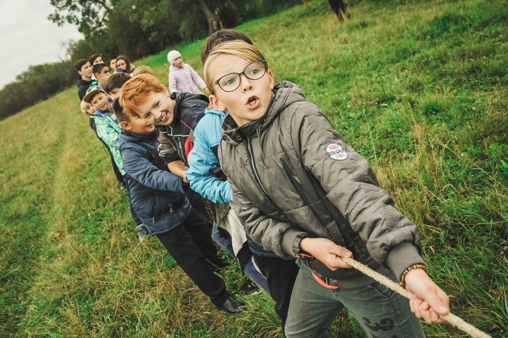 l'Intelligence relationnelle est un jeu d'enfant comme illustré par ce groupe d'enfants dans un champs, tirant tous dans la même direction sur une corde dans un jeu de tir à la corde