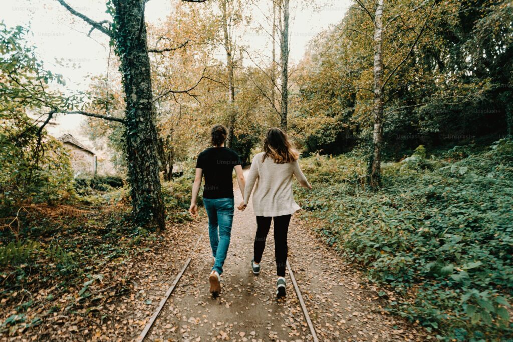 Couple marchant main dans la main sur un chemin en forêt lors d’un week-end couple.